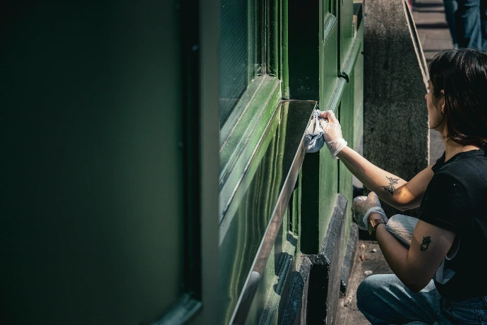 A person cleaning a green metal structure with a cloth